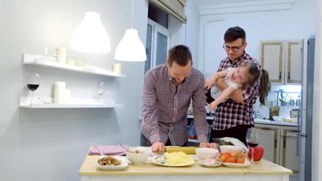 Familia-gay-con-hija-niño-cocinar-pizza-juntos-en-la-cocina-y-abrazando.