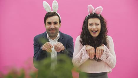 Young-couple-are-beautiful-on-pink-background.-During-this-time,-they-are-dressed-in-rabble-ears.-Looking-at-each-other,-speaking-and-smiling,-behave-like-rabbits.