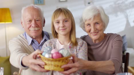 Mädchen-und-Großeltern-halten-Korb-mit-Eggen