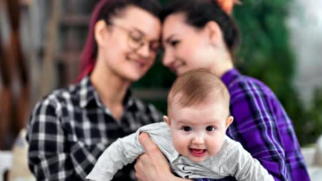 Close-up-little-cute-baby-holding-by-hand-of-same-sex-couple-having-good-time-together-at-home