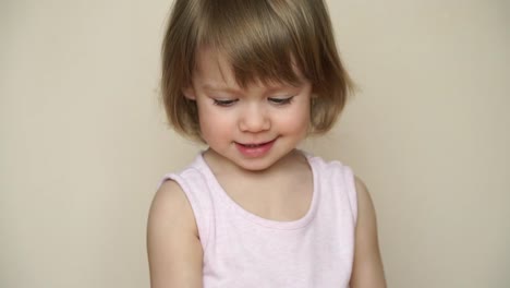 Portrait-of-little-pretty-smiling-caucasian-girl-holds-chicken-egg-decorated-for-Easter-chick,-with-painted-muzzle-with-eyes-and-bow.