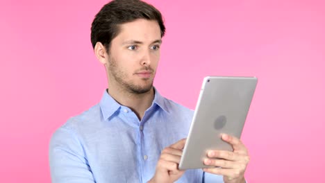 Young-Man-Using-Tablet-on-Pink-Background