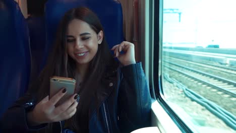 Porträt-des-attraktiven-lächelnden-Mädchen-im-Zug-mit-Smartphone-im-Chat-mit-Freunden-Frau-Hand-Internet-Technologie-Mobilfunk-Stadt-Smartphone-Smartphone-Trasse-Transport-jung