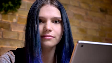 Retrato-de-primer-plano-de-joven-hermosa-mujer-hipster-caucásica-con-el-pelo-temitado-usando-la-tableta-y-mirando-la-cámara-en-casa-acogedora