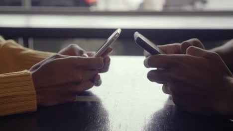 Couple-using-their-mobile-phones-in-cafe