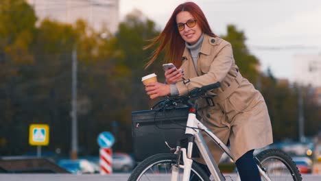 Mujer-de-negocios-consumada-en-bicicleta-con-teléfono-móvil-fuera