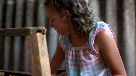 Unrecognizable-kids-with-their-grandmother-feed-the-rabbits-in-the-barn.-Black-rabbits-eat-green-leaves-in-the-pen.