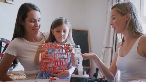 Pareja-femenina-del-mismo-sexo-haciendo-robot-de-kit-con-su-hija-en-casa-juntos