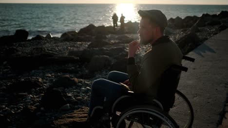 El-usuario-masculino-de-la-silla-de-ruedas-está-mirando-al-mar-y-pensando-en-la-noche-de-primavera