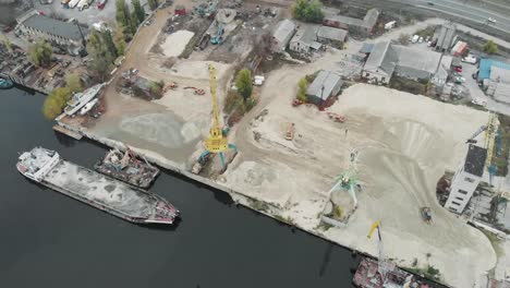 Hafenfrachtkrane-fördern-Flusssand,-Produktion.-Arbeitsladung-gelbe-Kräne-arbeiten-mit-Sand-in-Industriestadt-mit-Smog-und-Nebel