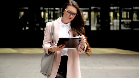 Young-Successful-Brunette-Business-Woman-is-Walking-Through-the-City-With-Documents-and-Using-Her-Smartphone