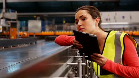 Weibliche-Supervisorin-mit-digitalem-Tablet-in-der-Nähe-der-Produktionslinie