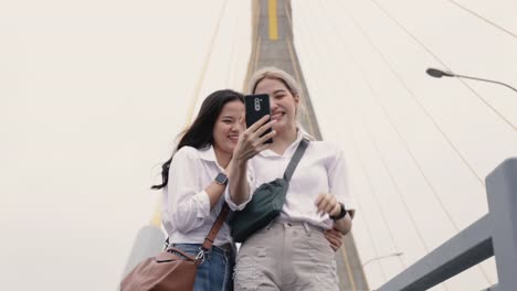 Happy-Asian-lesbian-couples-selfie-video-chat-with-friends-enjoying-traveling-in-Thailand.-Beautiful-young-women-having-fun-in-vacation-time.-LGBT-concept.