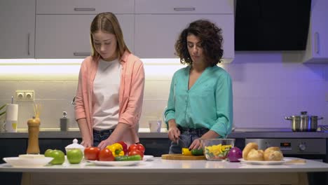 Mujeres-bonitas-cocinando-en-casa,-cortando-verduras-frescas-en-la-mesa-de-la-cocina,-salud