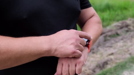 overweight-adult-man-in-a-black-sports-uniform-raised-his-hand-on-which-a-smart-watch-is-dressed,-the-athlete-flips-through-the-applications