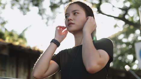 Mujer-asiática-trotando-haciendo-ejercicio-corriendo-escuchando-música-en-el-bosque-de-otoño-en-un-día-cálido-y-soleado.