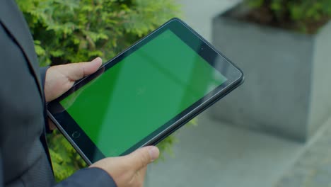 Overhead-view-businessman-browsing-internet-online-on-digital-tablet-outdoors.-Close-up-business-man-working-on-touchpad-on-street.-Male-hands-typing-on-pad-with-green-screen-in-slow-motion.