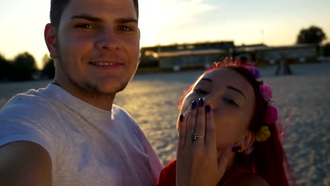 Beautiful-lovers-on-video-calling-their-friends-from-beach-at-sunset