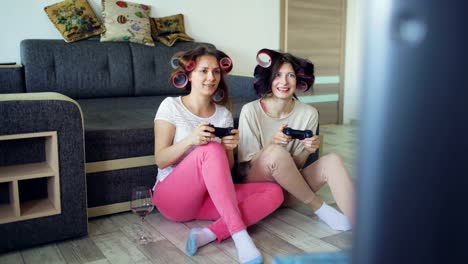 Zwei-lustige-Frauen-spielen-Konsolenspiele-mit-Gamepad-und-haben-Spaß-zu-Hause