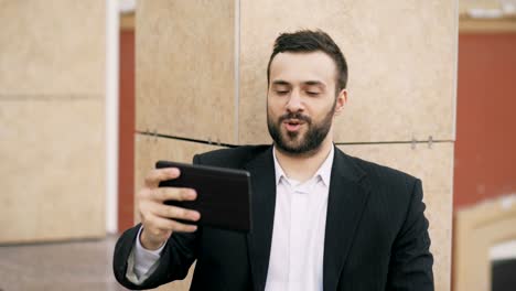 Joven-empresario-hablando-por-tablet-PC-tener-video-chat-con-su-esposa.-Hombre-de-negocios-usando-la-aplicación-para-tener-conversación-de-video-conferencia-con-su-familia-durante-las-vacaciones-de