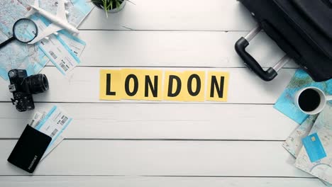 Top-view-time-lapse-hands-laying-on-white-desk-word-"LONDON"-decorated-with-travel-items