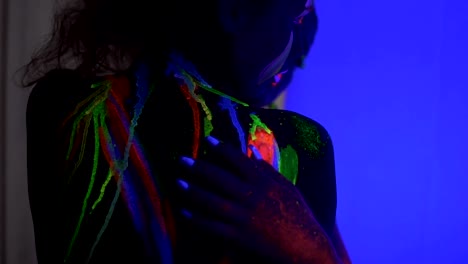 Closeup-view-of-two-beautiful-girls-with-fluorescent-makeup-and-body-art-under-UV-black-light-petting-each-other-and-hugging.-Slowmotion-shot