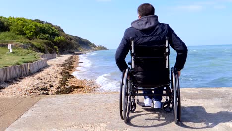 Rückseite-des-behinderten-Menschen-im-Rollstuhl-am-Strand