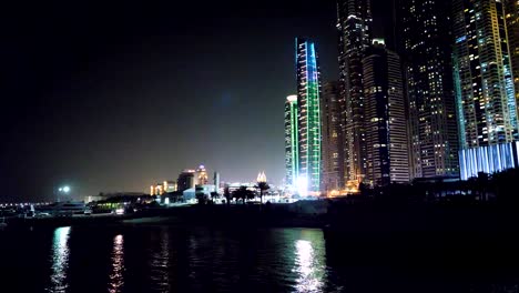 Dubai-downtown-por-la-noche-reflejado-en-el-agua.-Ciudad-en-escena-noche,-panorámica-de-la-ciudad-reflejada-en-el-agua,-Dubai.-Dubai-downtown-por-la-noche-con-el-reflejo-en-el-agua,-diseño-moderno-de-la-ciudad-de-nueva