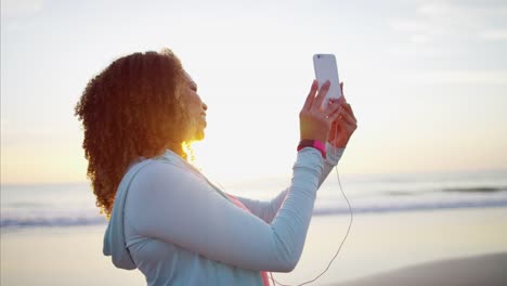 Ethnische-weibliche-winken-mit-interaktiven-Technologie-am-Strand