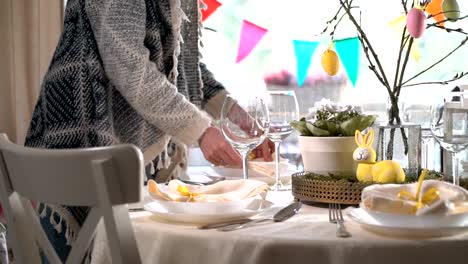 Junge-Frau,-die-festlichen-Ostertisch-mit-Hasen-und-Eiern-Dekoration-festlegen