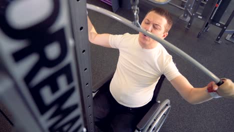 Top-view-of-an-invalid-in-a-wheelchair-pulling-a-metal-bar-and-lifting-weight