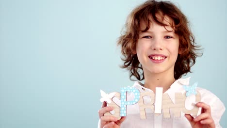 A-red-haired,-curly-haired-boy-in-a-white-shirt-is-holding-a-spring-decor.-Portrait-in-studio