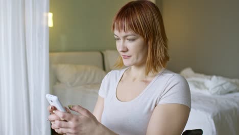 Sonriente-mujer-en-silla-de-ruedas-de-mensajes-de-texto-en-el-teléfono-móvil