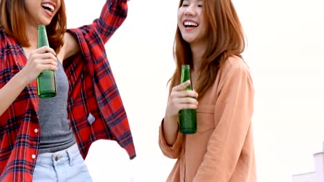 Young-asian-woman-lesbian-couple-dancing-and-clinking-bottles-of-beer-party-on-rooftop.