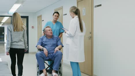 In-the-Hospital-Hallway,-Nurse-Pushes-Elderly-Patient-in-the-Wheelchair,-Doctor-Talks-to-Them.-Clean,-New-Hospital-with-Professional-Medical-Personnel.