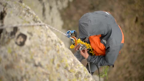 Close-up-of-a-rock-climber-hanging-on-a-rope-and-unraveling-carbines-and-insurance