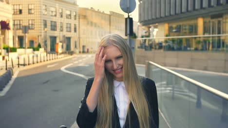 Formal-business-woman-walking-on-street.-Elegant-blond-woman-in-suit-standing-on-street-with-smile-against-urban-background