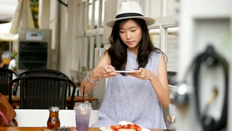 Young-asian-woman-take-a-photo-pancake-at-cafe.-Technology-and-social-networks-concept.