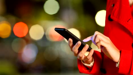 Mano-de-mujer-navegación-por-teléfono-una-noche-de-invierno