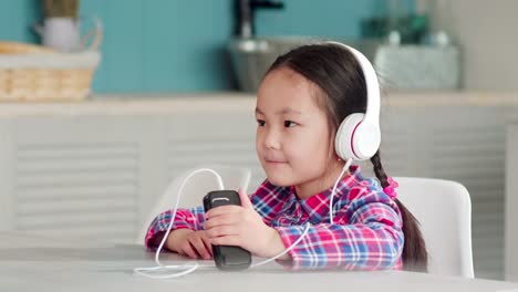 Niña-asiática-en-auriculares-escuchando-música-en-el-Smartphone