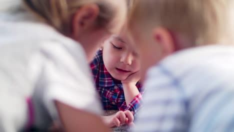 Kinder-liegen-im-Bett-und-spielen-am-Tablet