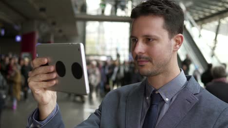 Caucasian-employee-working-online-and-mobile-at-train-station-with-digital-tablet