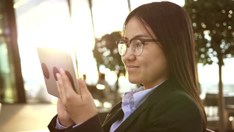 Mujer-bonita-joven-navegando-por-internet-con-tableta-digital-en-edificio-público