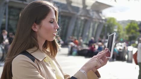 Good-looking-young-female-working-on-digital-tablet-in-public-space-outside