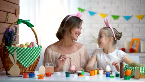 Little-daughter-kissing-mother-on-cheek-helping-with-Easter-eggs-decor,-love