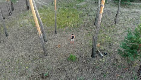 Man-controls-the-drone-in-a-pine-forest.-Quadrocopter-removes-the-man-and-moves-away-from-him