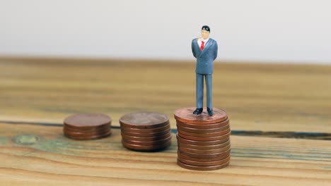 Miniature-people-standing-on-piles-of-coins