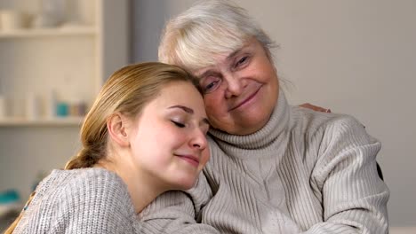 Aufmerksame-junge-Dame-Verkleidung-deaktiviert-Oma-im-Rollstuhl-mit-Karomuster,-umarmen