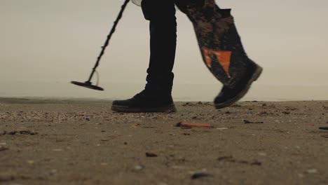 treasure-hunter-walking-along-the-sea-along-the-sand-with-a-metal-seeker