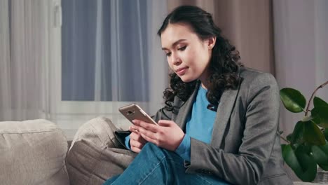 Sad-businesswoman-text-messaging-on-mobile-phone-at-home